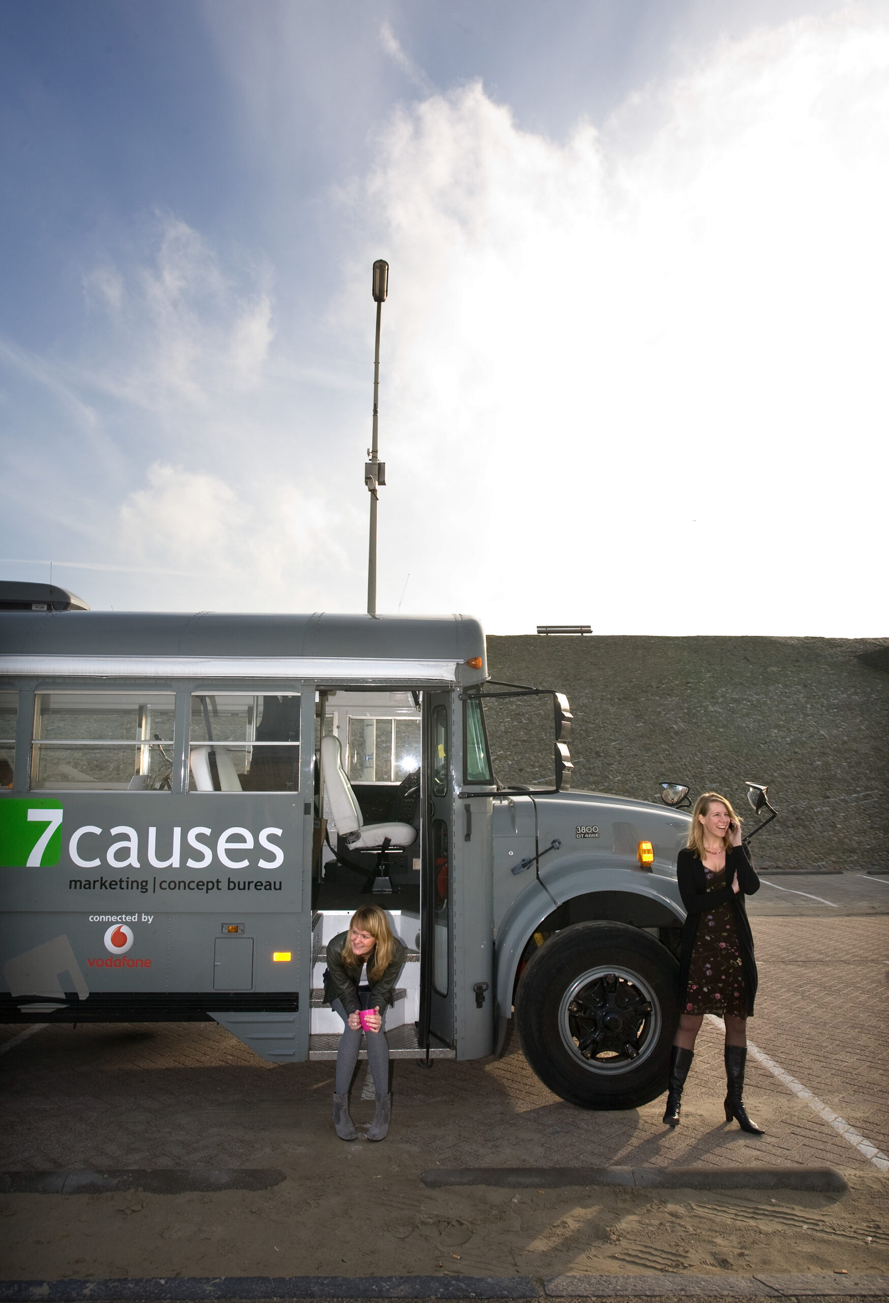 twee dames die bij een amerikaanse schoolbus poseren, de schoolbus is het mobiele kantoor van 7causes